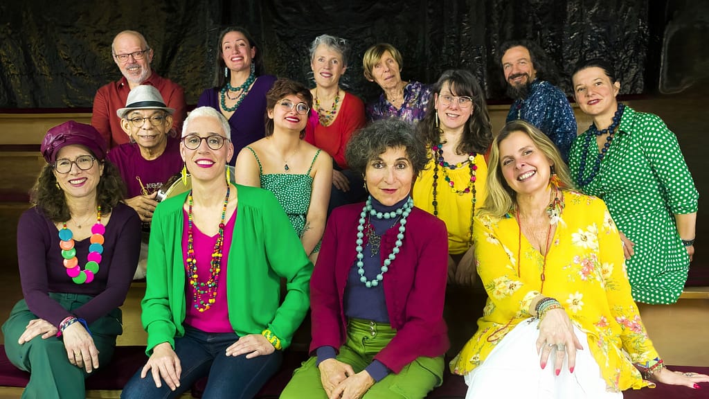 Le groupe Espace Tempo assis en gradin, tenues colorées – Photo : Raphaelle Bois
